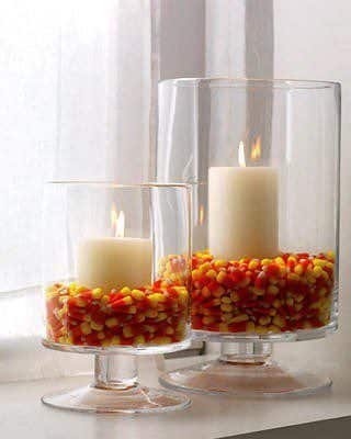 glass vases filled with candy corn and candles