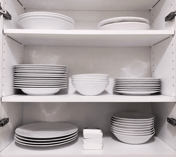 close up of white cupboard with all white dishes