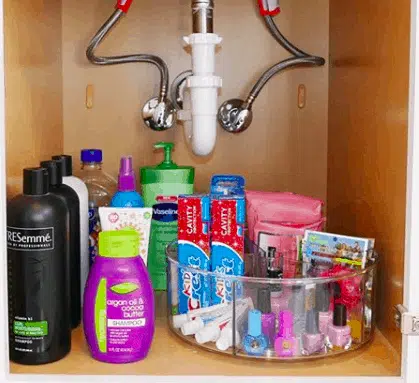 under sink storage with a lazy susan filled with toothpaste and cosmetics