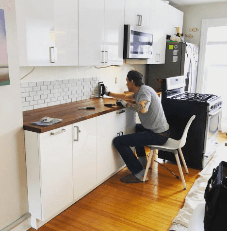 A man installing subway tile during a kitchen renovation