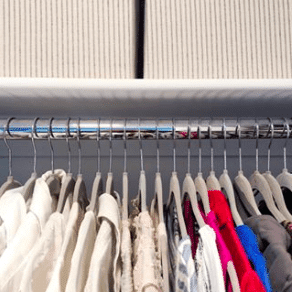 a closet with evenly spaced shirts on hangers