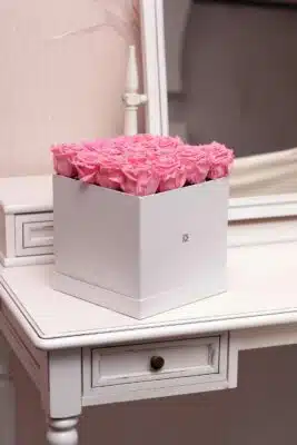 box of pink cut roses on a white dresser