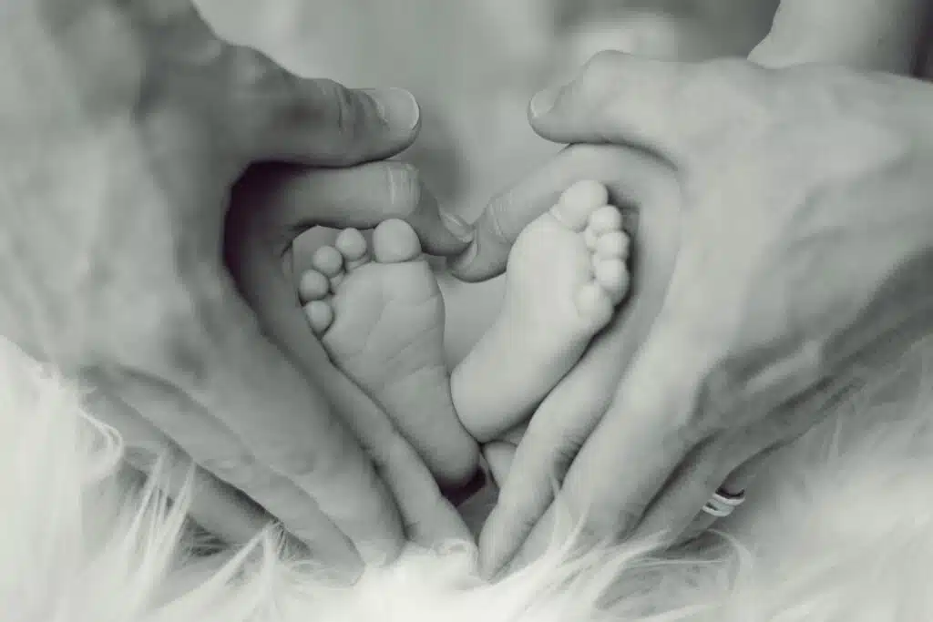 parent hands holding baby's feet in a heart