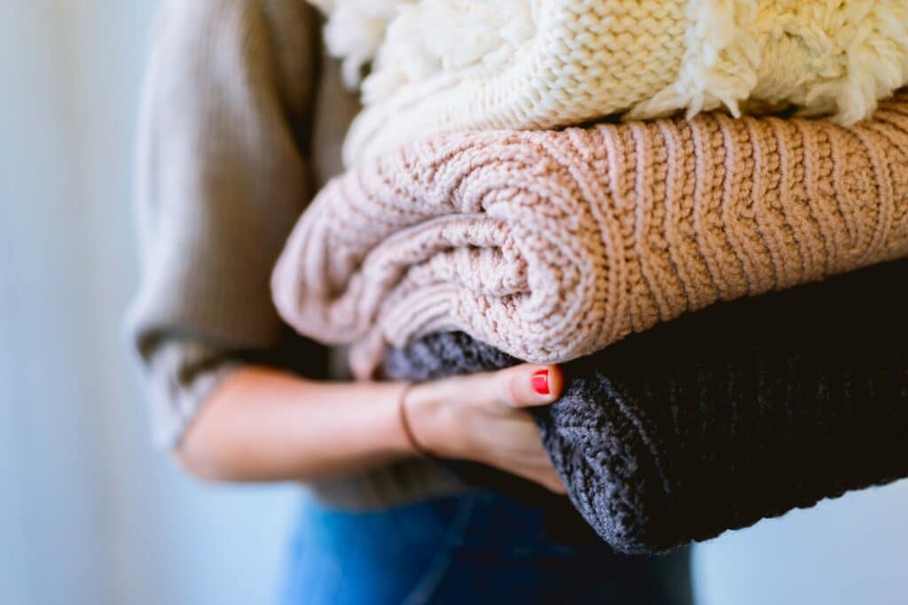 A woman carrying folded sweaters
