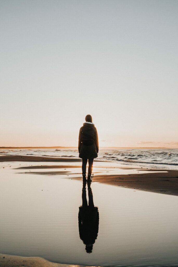 woman standing on a beach with reflection below her