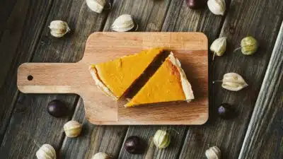 two slices of pumpkin pie on a wooden cutting board