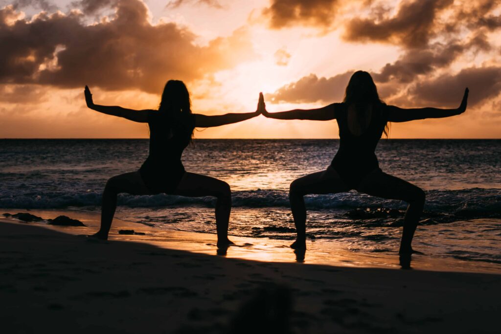 Two women doing yoga at sunrise