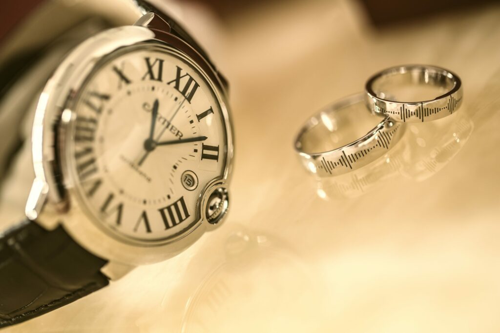 two silver rings to the right of a silver analog watch