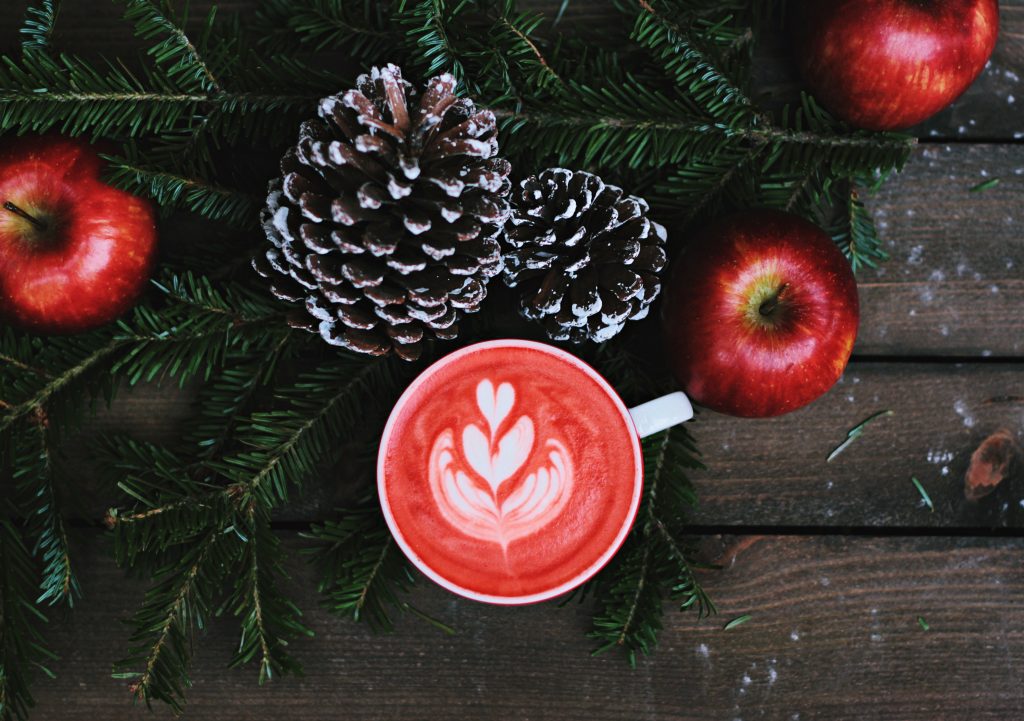 a cup of coffee with hearts and winter greenery