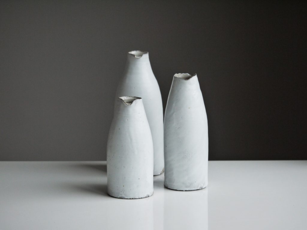 three white vases set against a black background